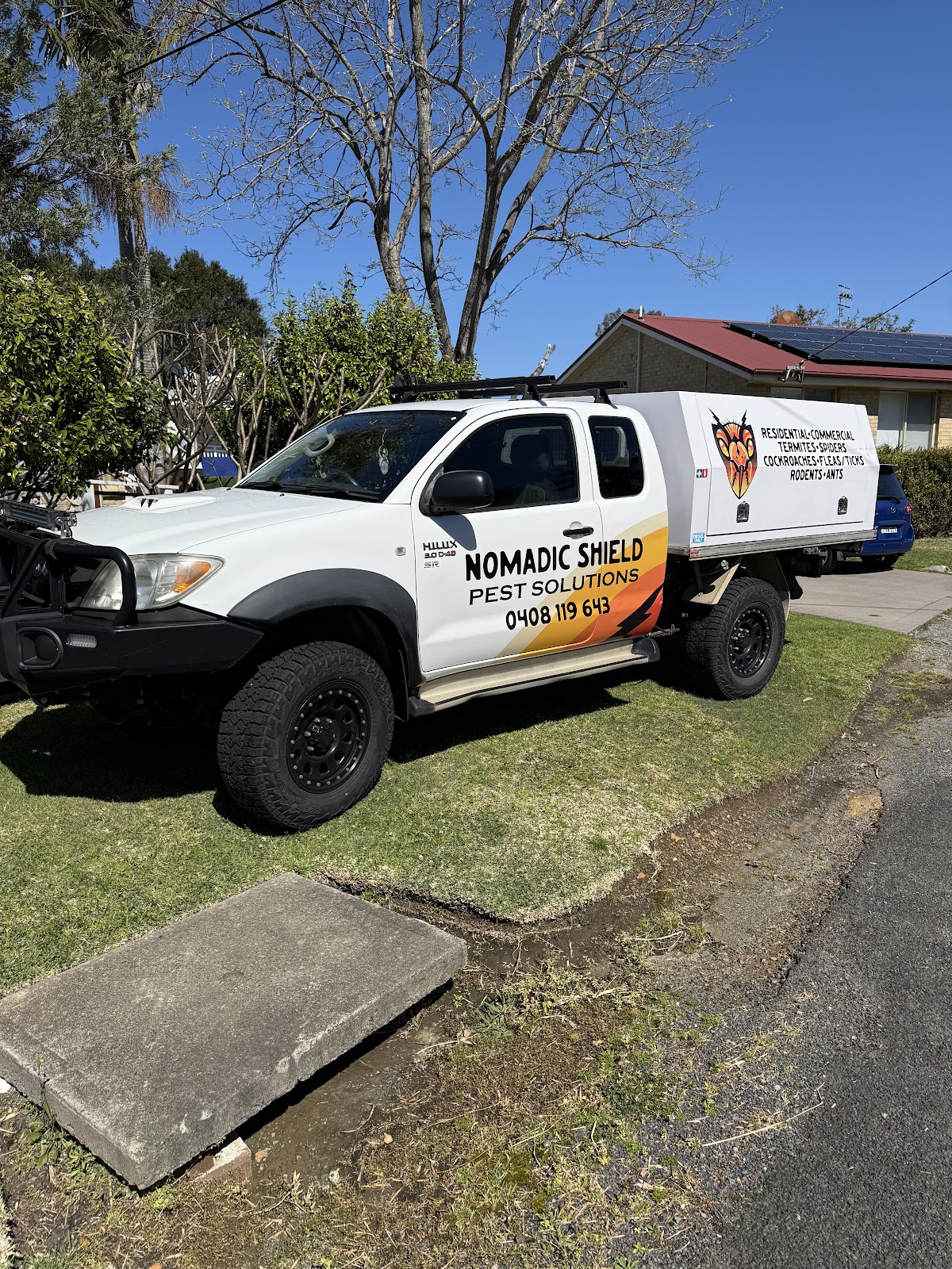 The Nomadic Shield Pest Solutions ute, a white Hilux with the crest and phone number on the side